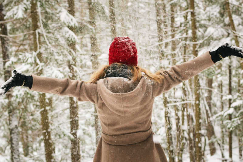 Girl in red winter hat in snowy forest
